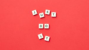 Motivational phrase 'Just Do It' spelled with Scrabble letters on a red background.